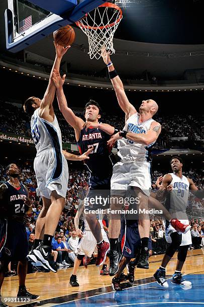 Zaza Pachulia of the Atlanta Hawks puts a shot up against Ryan Anderson and Marcin Gortat of the Orlando Magic in Game One of the Eastern Conference...
