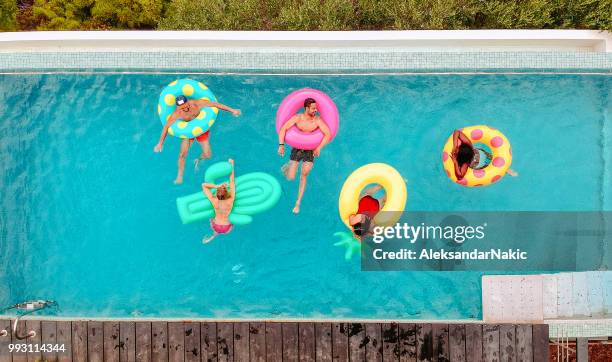 freunde, die spaß auf aufblasbaren ringen im pool - friends donut stock-fotos und bilder