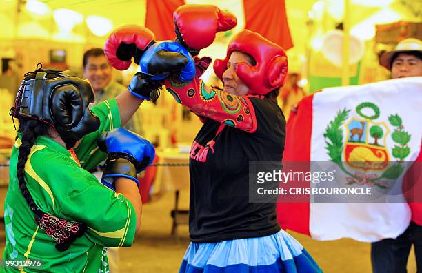 Man waves a Peruvian flag as two Andean peasant women representing Peru and Bolivia, measure themselves in a boxing ring on May 13 promoting a fair...