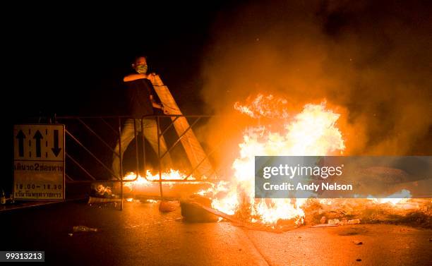 An anti-government Red Shirt protester adds to a burning barricade in the streets on May 14, 2010 in Bangkok, Thailand. So far more than 100 people...