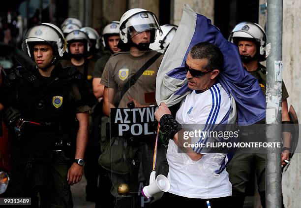 Demonstrators carries the Greek flag in front of police officers during a protest in central Athens against Turkey's Prime Minister Recep Tayyip...