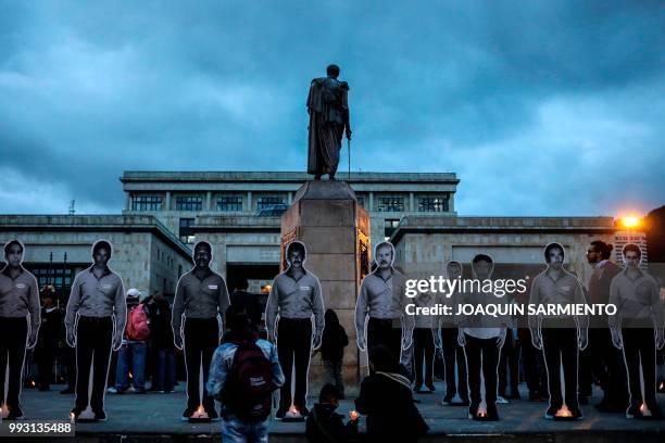 The figures of murdered activists are placed next to candles during a protest aat the Bolivar square in Bogota on July 6, 2018. - The UN urged the...