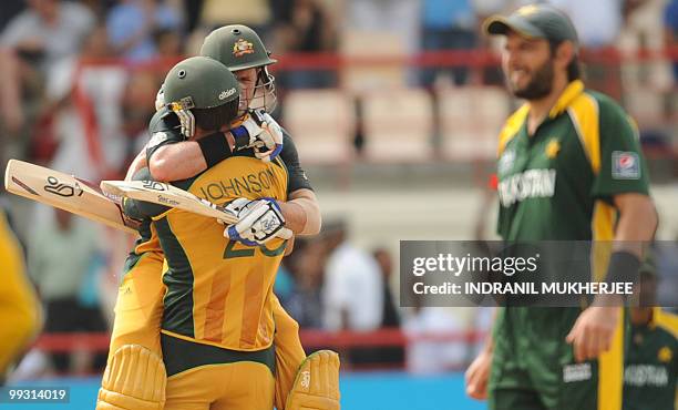 Pakistani cricket captain Shahid Afridi walks past Australian cricketer Mike Hussey and Mitchell Johnson celebrating after winning the ICC World...