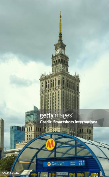 palace of culture and science ("palac kultury i nauki" - pkin) against dramatic sky and with metro station in foreground in warsaw, poland - warsaw spire stock pictures, royalty-free photos & images