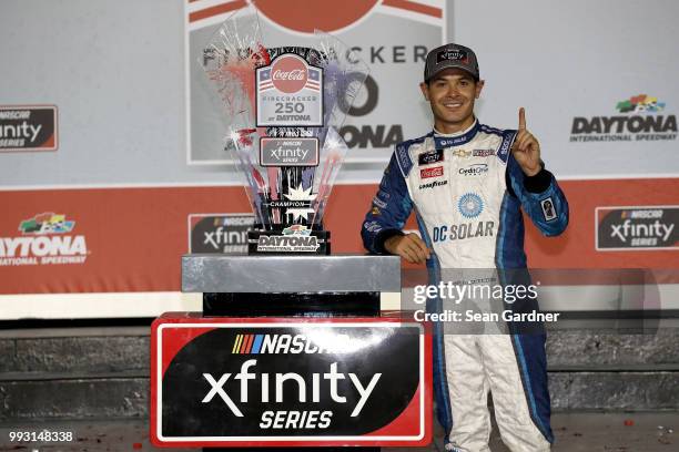 Kyle Larson, driver of the DC Solar Chevrolet, poses with the trophy in Victory Lane after winning the NASCAR Xfinity Series Coca-Cola Firecracker...