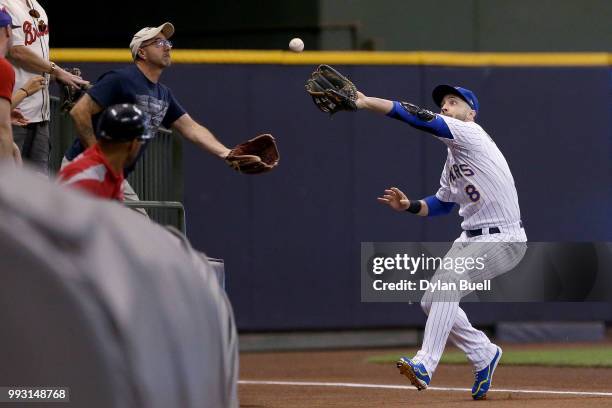Ryan Braun of the Milwaukee Brewers and a fan reach to catch a fly ball in the seventh inning against the Atlanta Braves at Miller Park on July 6,...