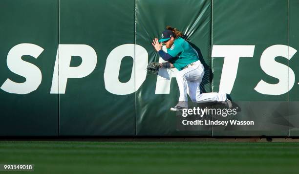 Ben Gamel of the Seattle Mariners runs into the center field wall while trying to catch an RBI triple by Tony Wolters of the Colorado Rockies in the...