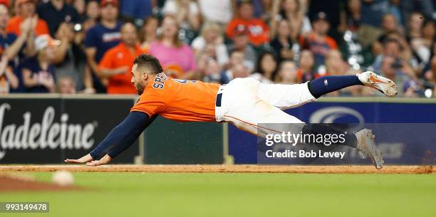 George Springer of the Houston Astros dives into third base against the Chicago White Sox at Minute Maid Park on July 6, 2018 in Houston, Texas.