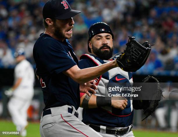 Chris Sale starting pitcher of the Boston Red Sox avoids colliding with Sandy Leon as he catches a foul ball hit by Mike Moustakas of the Kansas City...