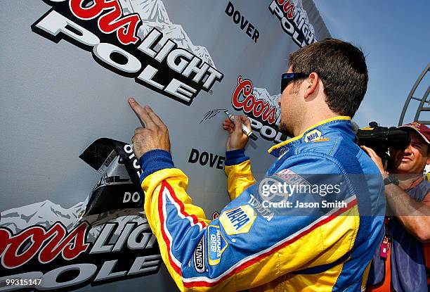 Martin Truex Jr., driver of the NAPA Auto Parts Toyota, signs the wall in Victory Lane after qualifying for the pole position in the NASCAR Sprint...