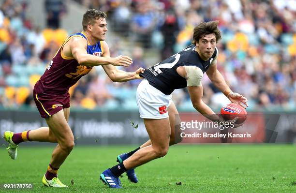 Caleb Marchbank of Carlton is pressured by the defence of Tom Cutler of the Lions during the round 16 AFL match between the Brisbane Lions and the...