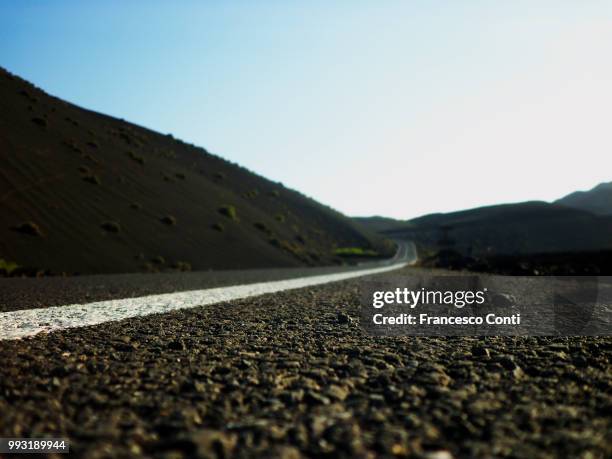 lanzarote, carretera en el parque nacional de timanfaya - carretera stock pictures, royalty-free photos & images