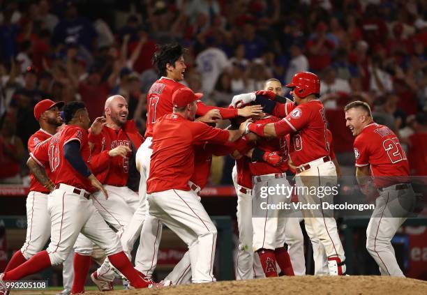 Ian Kinsler of the Los Angeles Angels of Anaheim is mobbed by teammates after hitting a single to right field which resulted in the winning run...