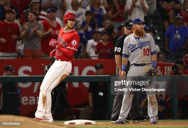 Shohei Ohtani of the Los Angeles Angels of Anaheim stops at third base as Justin Turner of the Los Angeles Dodgers looks on during the ninth inning...