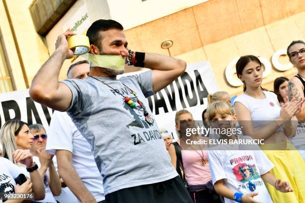 Davor Dragicevic, father of a student found dead in a stream in March, symbolicaly puts duct tape over his mouth during the 100th day of a...