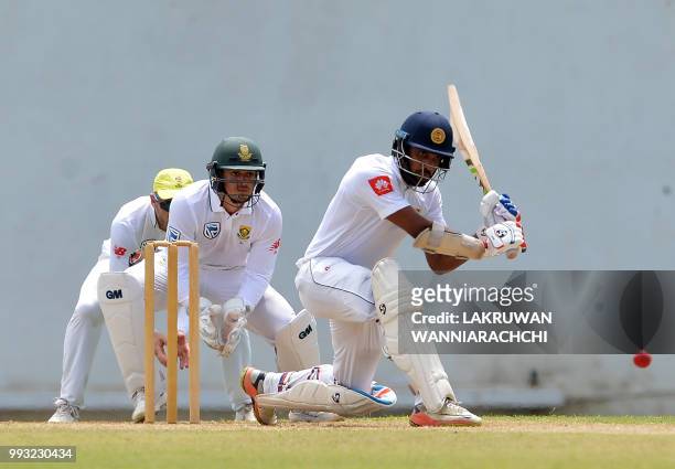 Danushka Gunathilaka of Sri Lanka Board XI is watched by South African wicketkeeper Quinton de Kock as he plays a shot during the opening day of a...