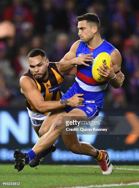 Luke Dahlhaus of the Bulldogs is tackled by Jarman Impey of the Hawks during the round 16 AFL match between the Western Bulldogs and the Hawthorn...