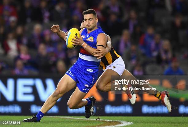 Luke Dahlhaus of the Bulldogs is tackled by Jarman Impey of the Hawks during the round 16 AFL match between the Western Bulldogs and the Hawthorn...