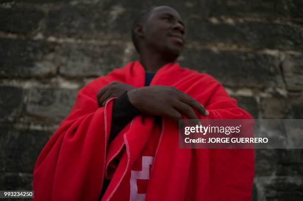 Migrants keeps warm with a Red Cross blanket after arriving aboard a coast guard boat at Tarifa's harbour on July 7 after an inflatable boat carrying...