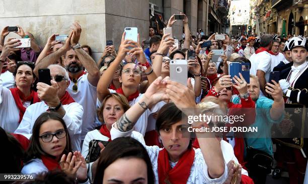 People take pictures during the procession of Pamplona´s patron Saint Fermin on the first day of the San Fermin bull run festival in Pamplona,...