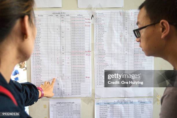 People look at the list containing the names of all passengers onboard a capsized tourist boat for updates on rescue search at the Vachira Phuket...