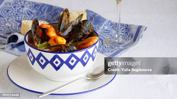 french soup bouillabaisse with mussels, clams, langoustines, squid, cod, trout in white bowl with bl - bouillabaisse stock pictures, royalty-free photos & images