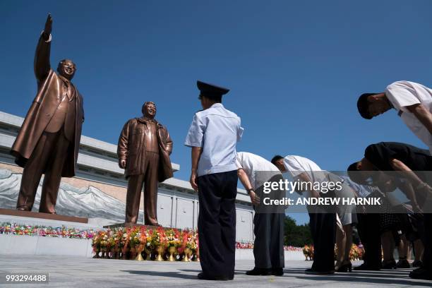 People pay their respects in front of bronze statues of the late leaders Kim Il Sung , and Kim Jong Il at Munsu Hill in Pyongyang on July 7, 2018.