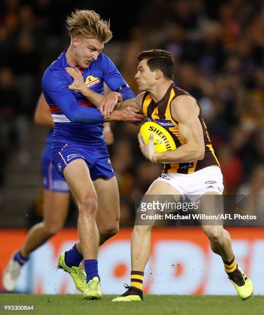 Jaeger O'Meara of the Hawks fends off Shane Biggs of the Bulldogs during the 2018 AFL round 16 match between the Western Bulldogs and the Hawthorn...