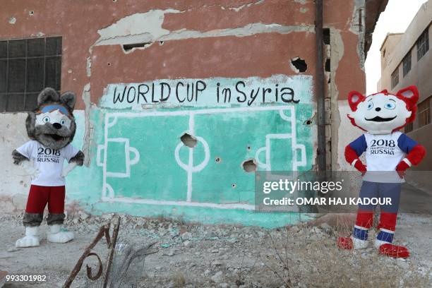 Two Syrian activists wearing the cat and wolf Russia 2018 World Cup mascot's outfits perform during an event to protest against the bombings in...