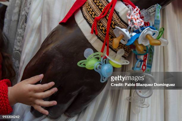 Child touches the hand of a giant carrying babies dummies during the Comparsa de Gigantes y Cabezudos, or Giants and Big Heads parade on the second...