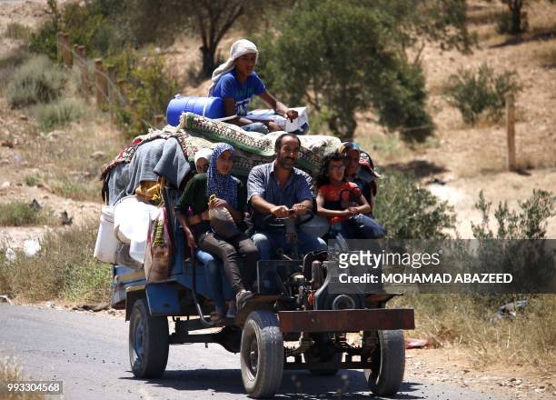 Syrians ride a vehicle carrying their personal belongings as they return to their homes in towns and villages situated on the eastern outskirts of...