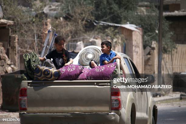 Children sit atop a pickup truck carrying their family's personal belongings as displaced Syrians return to their homes in towns and villages...