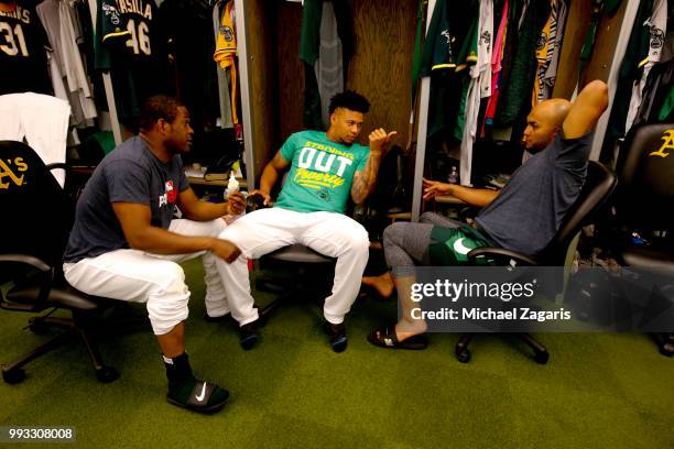 Santiago Casilla, Frankie Montas and Yusmeiro Petit of the Oakland Athletics talk in the clubhouse prior to the game against the Kansas City Royals...
