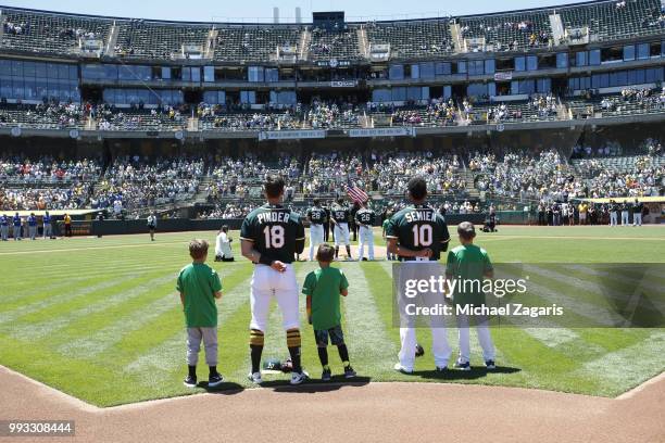 Chad Pinder and Marcus Semien the Oakland Athletics stand on the field with little leaguers during the anthem prior to the game against the Kansas...