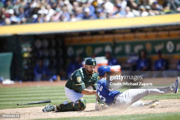 Whit Merrifield of the Kansas City Royals beats the tag at home by Jonathan Lucroy of the Oakland Athletics during the game at the Oakland Alameda...