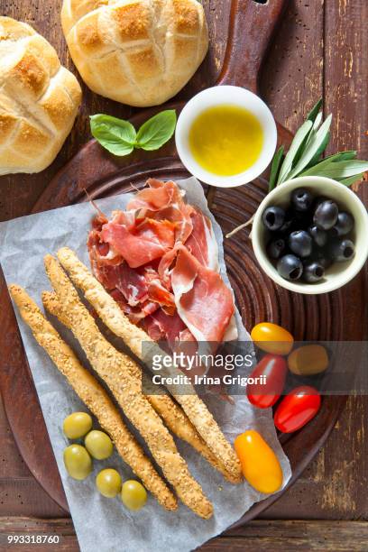 prosciutto crudo with bread, olives, tomatoes, bre - crudo stock-fotos und bilder