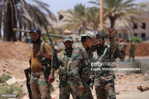 Syrian government soldiers stand flashing the victory gesture at the Nassib border crossing with Jordan in the southern province of Daraa on July 7,...