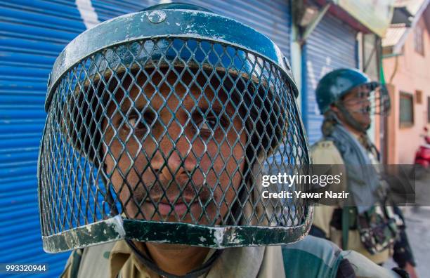 Indian government forces stand guard in front of shuttered shops during a strike on July 8, 2018 in Srinagar, the summer capital of Indian...