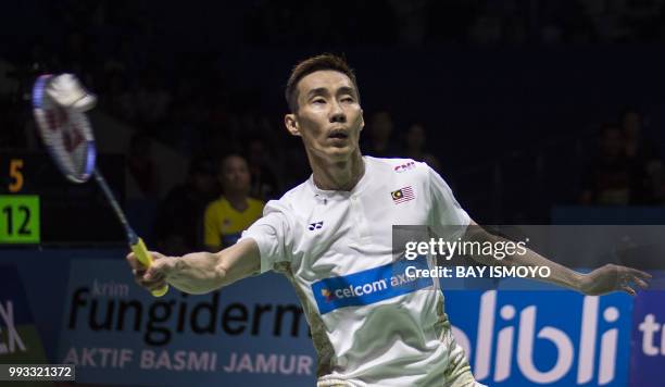 Lee Chong Wei of Malaysia hits a return against Kento Momota of Japan during their men singles semi-final match at the Indonesia Open badminton...