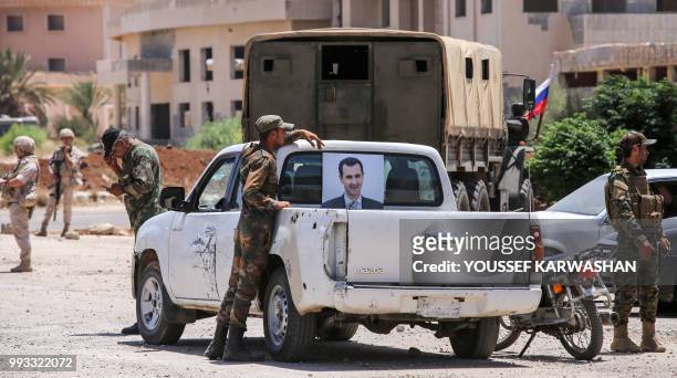 Syrian government soldier stands next to a pickup truck bearing the image of President Bashar al-Assad at the Nassib border crossing with Jordan in...