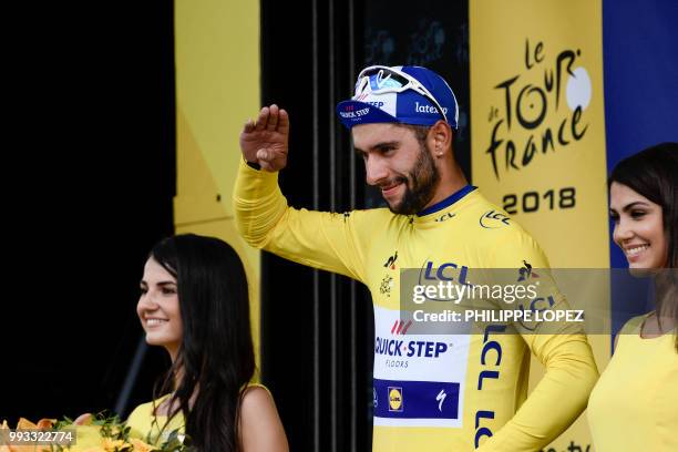 Colombia's Fernando Gaviria, wearing the overall leader's yellow jersey, celebrates on the podium after winning the first stage of the 105th edition...