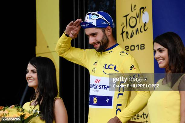 Colombia's Fernando Gaviria, wearing the overall leader's yellow jersey, celebrates on the podium after winning the first stage of the 105th edition...