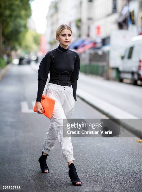 Caroline Daur wearing orange Prada clutch, black turtleneck, Prada heels, white track suit pants is seen outside Viktor & Rolf on day four during...