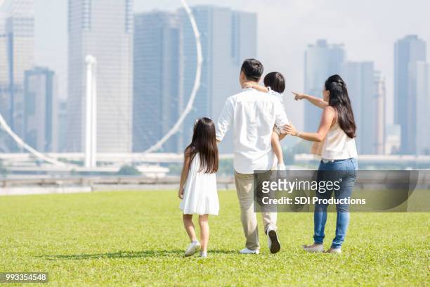 rückansicht der familie gemeinsam gehen - asian family in park stock-fotos und bilder