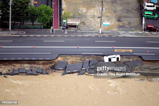 In this aerial image, a car falls as the road has been eroded by floodwater on July 7, 2018 in Hiroshima, Okayama, Japan. At least two person were...