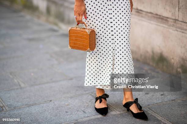 Guest wearing white dress with black dots print, brown mini bag, black pointed flats is seen outside Valentino on day four during Paris Fashion Week...