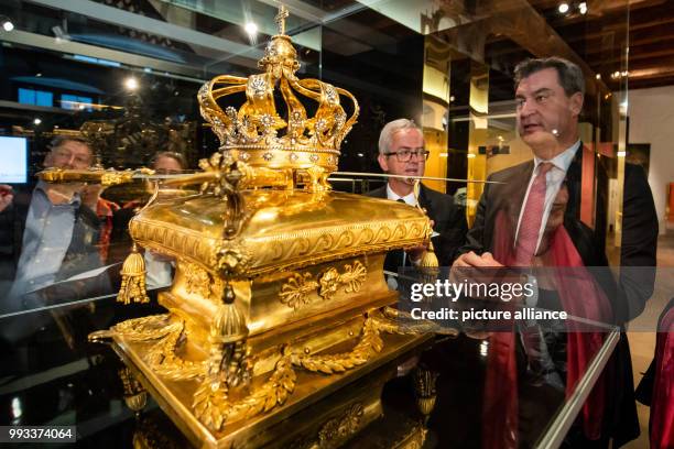 July 2018, Germany, Nuremberg: Bavarian Minister President Markus Soeder of the Christian Social Union inspects golden crowning treasures dating back...