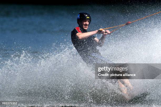 July 2018, Germany, Kirchheim: Water sportsman Max us pulled along on a toilet seat lid at a water skiing facility. Photo: Swen Pförtner/dpa