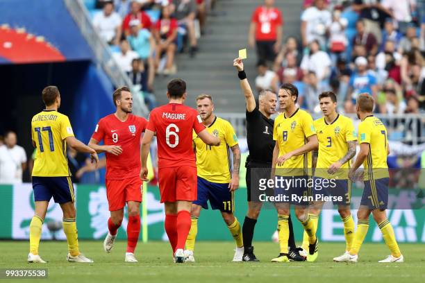 John Guidetti of Sweden and Harry Maguire of England receive a yellow card from Referee Bjorn Kuipers during the 2018 FIFA World Cup Russia Quarter...