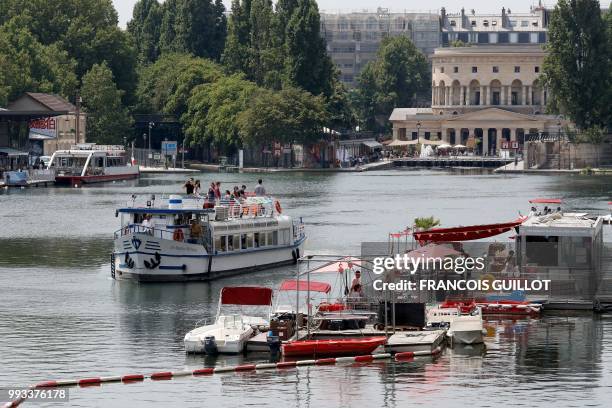 Bateau-mouche sails in the bassin de la Villette near the Rotonde of Stalingrad in Paris on July 7, 2018 during the 17th edition of Paris Plage...